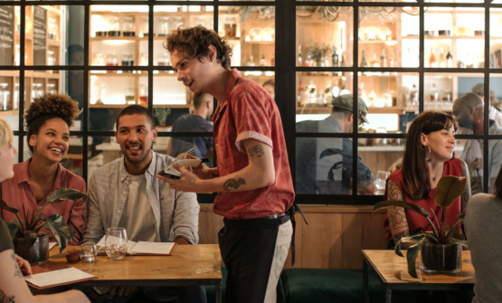 Waiter serving customers in a busy restaurant following advice by restaurant consultant