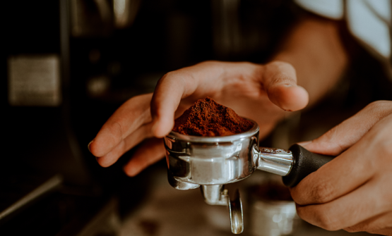 Coffee being filtered at an espresso machine by a barista