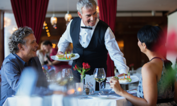 A waiter serving a couple at a table.