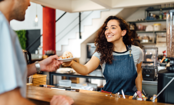Barista serving a customer at cafe with good hospitality business planning