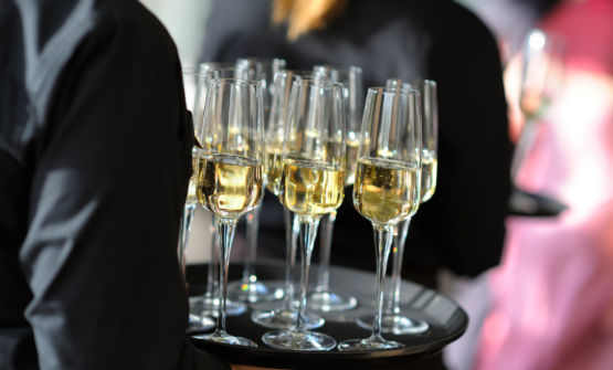 A waiter serving champagne for a catering company that has undertaken commercial advice.