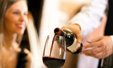 sommelier pouring wine for a diner at a busy restaurant